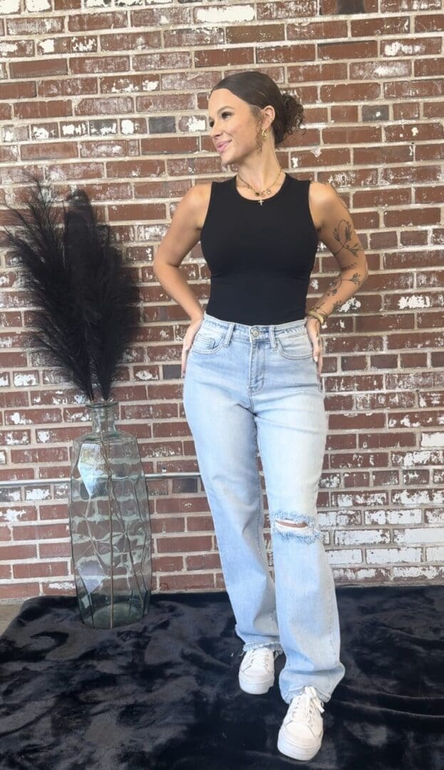 A woman standing in front of a brick wall.