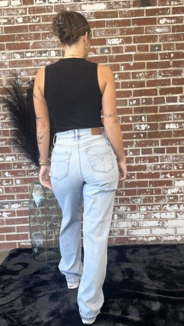 A woman standing in front of a brick wall.